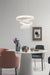 Modern dining room with a white spiral pendant light, round table, and colorful chairs.