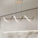 Modern pendant light fixture hanging above a dining table with marble backsplash.